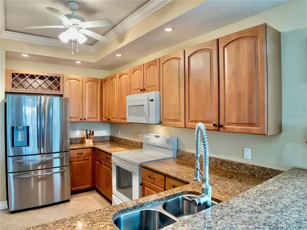 a kitchen with stainless steel appliances granite countertop a sink and a refrigerator
