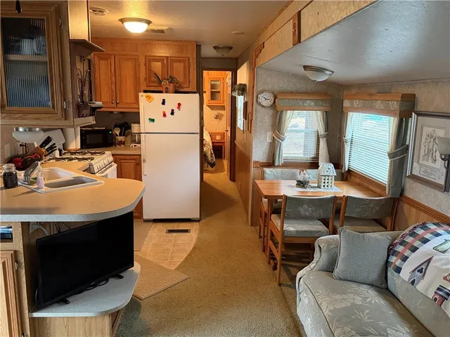 a living room with stainless steel appliances furniture a rug and a kitchen view