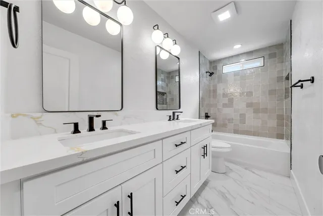 a bathroom with a double vanity sink toilet mirror and shower
