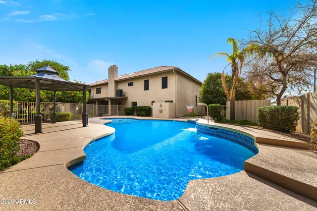 a view of an empty room with chandelier fan and wooden floor