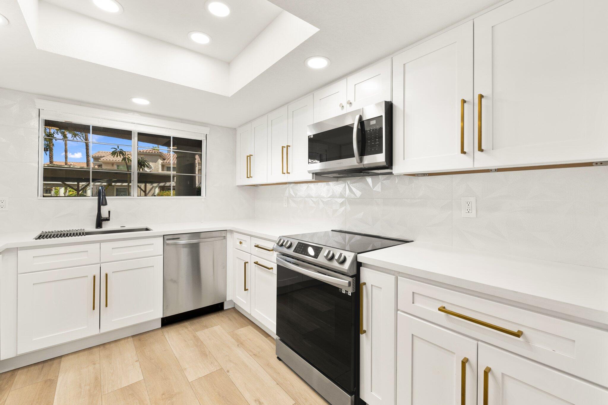 a kitchen with stainless steel appliances granite countertop white cabinets a microwave oven and a sink