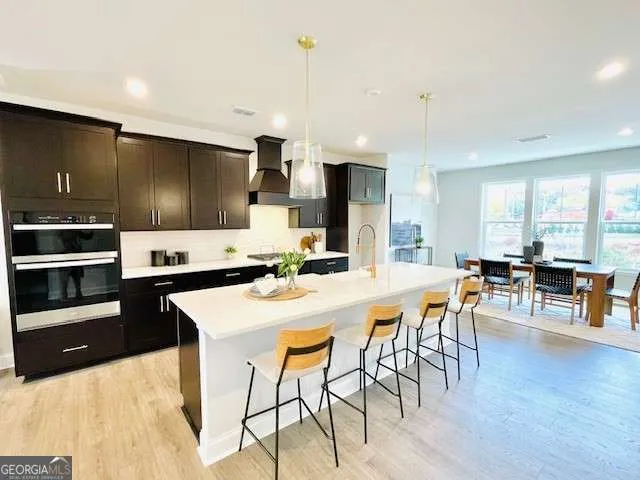 a kitchen with stainless steel appliances kitchen island granite countertop a stove a sink a dining table and chairs