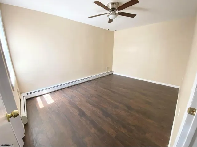 an empty room with wooden floor fan and windows