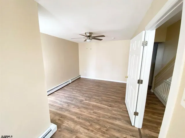 a view of a room with wooden floor and a ceiling fan