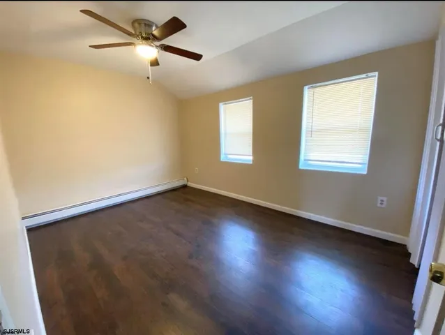 an empty room with wooden floor fan and windows