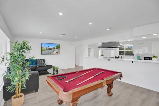 a living room with furniture pool table and a potted plant