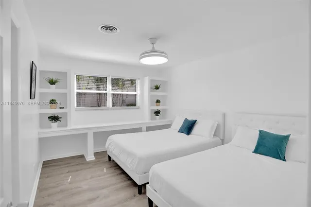 a bedroom with two beds and a window with kitchen view