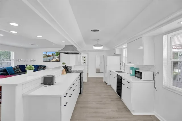 a large white kitchen with lots of counter space wooden floor and stainless steel appliances
