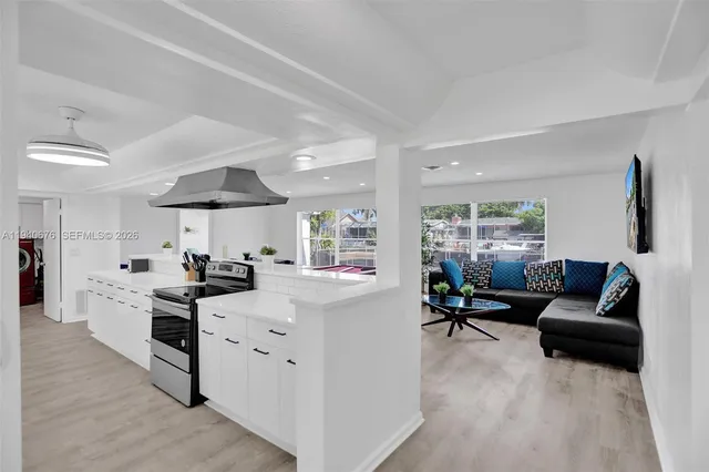 a view of living room kitchen with stainless steel appliances furniture stove and cabinets