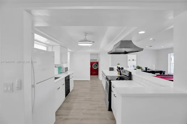 a large white kitchen with stainless steel appliances lots of counter space and window