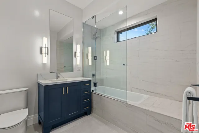 a bathroom with a bathtub shower sink mirror and toilet