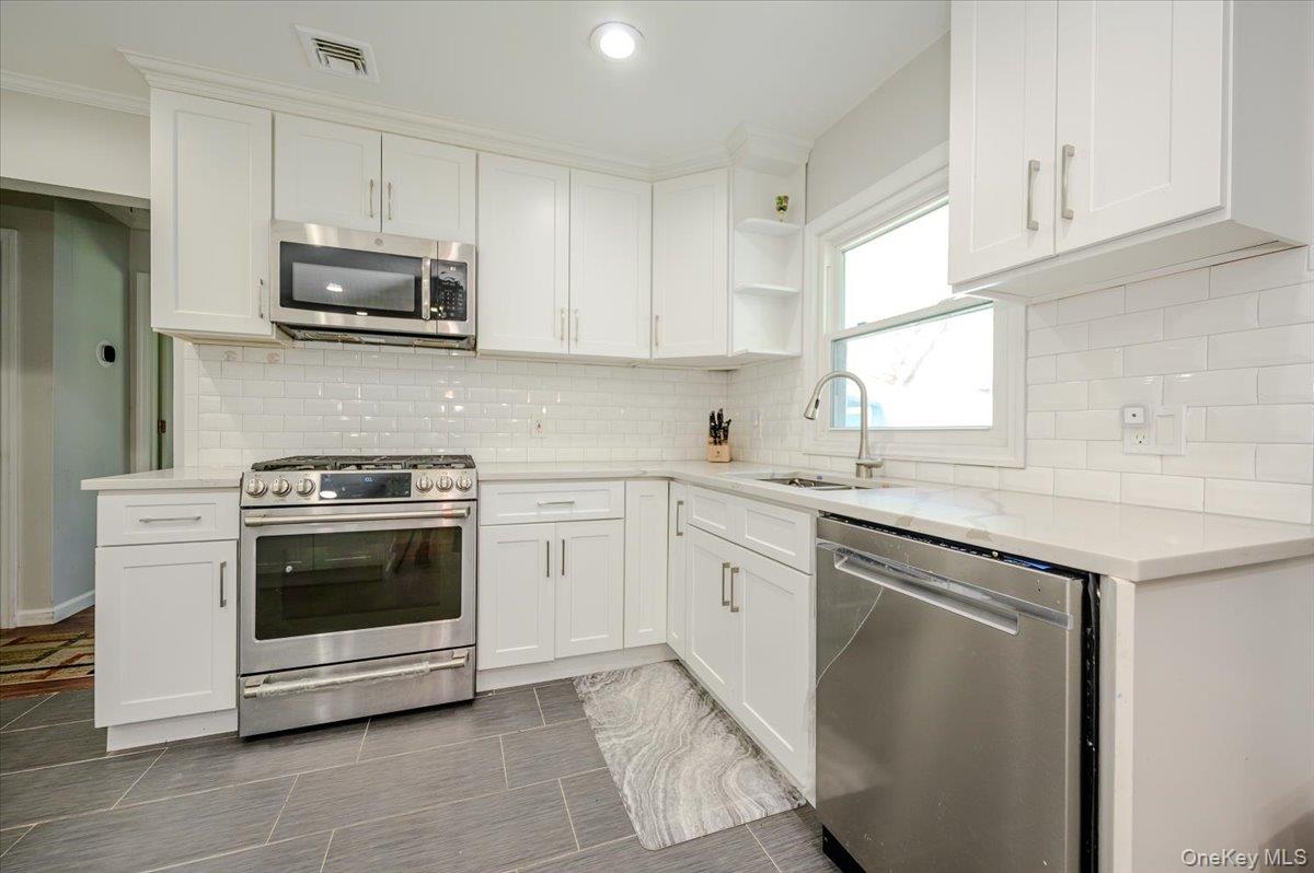 534 Allen Road Woodmere, NY 11598 - Photo 9 of 35 a kitchen with stainless steel appliances granite countertop a sink and a stove