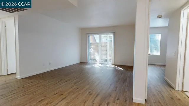 a view of an empty room with wooden floor and a window
