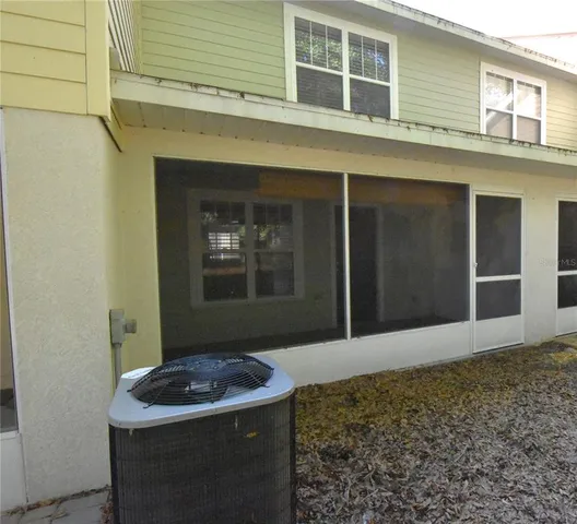 a view of a white house with a large tree and plants