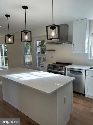 a kitchen with stainless steel appliances granite countertop a sink a stove and a wooden floor