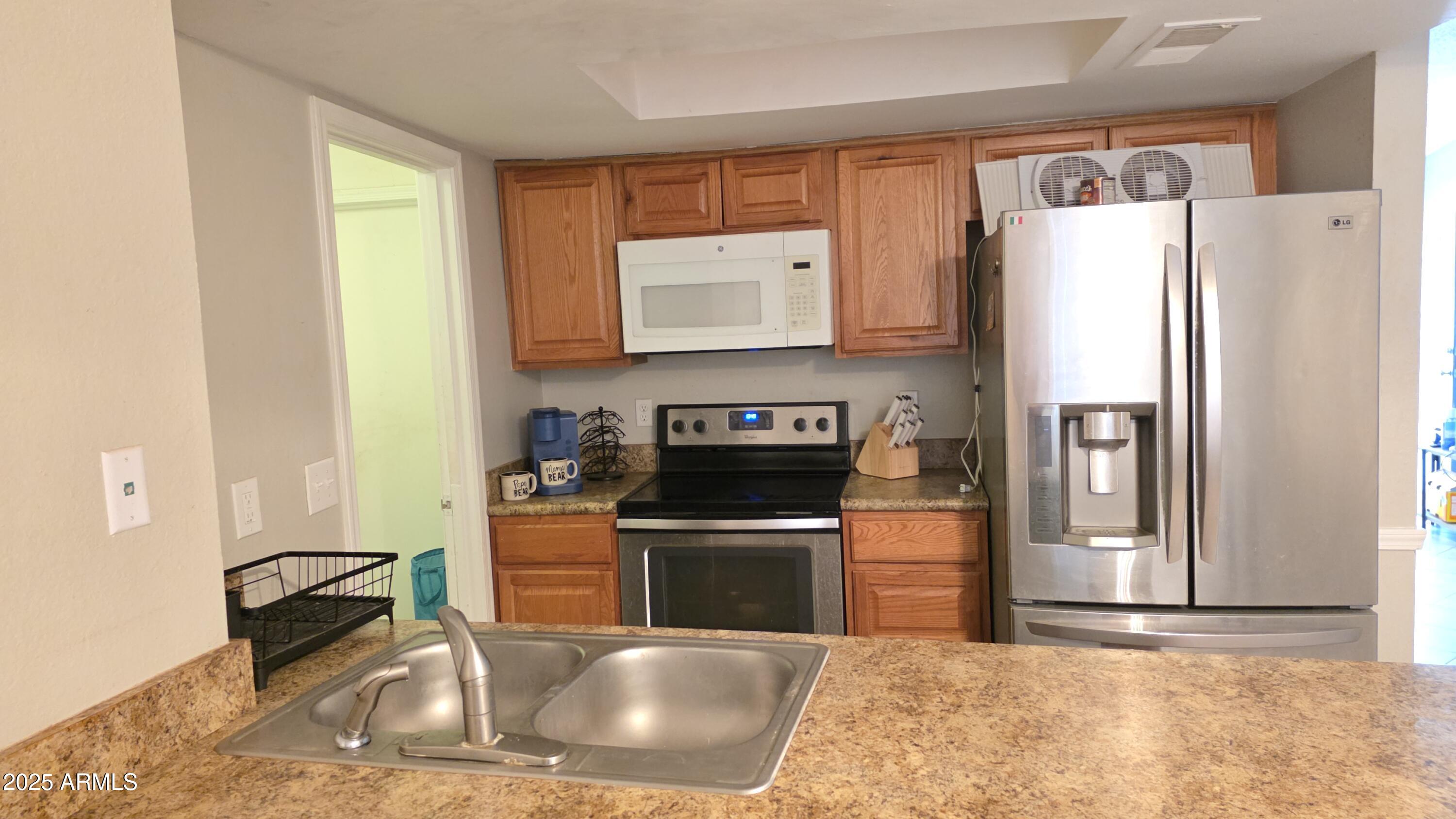 14900 South Capistrano Road Arizona City, AZ 85123 - Photo 7 of 24 a kitchen with stainless steel appliances granite countertop a refrigerator a stove and a sink with wooden floor