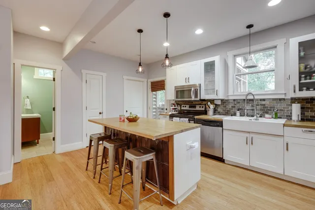 a kitchen that has a lot of cabinets in it with stainless steel appliances granite countertop a stove a sink a dining table and chairs