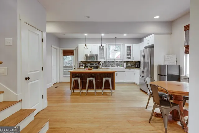 a kitchen with stainless steel appliances kitchen island granite countertop a table chairs sink and cabinets