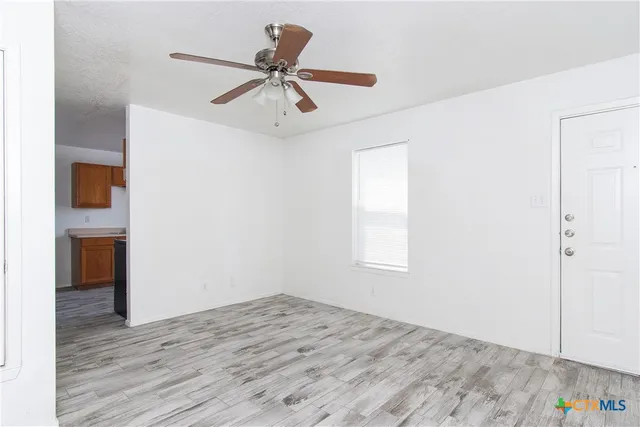 a view of empty room with wooden floor and ceiling fan