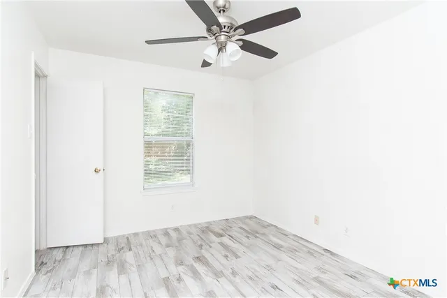 an empty room with a window and a ceiling fan