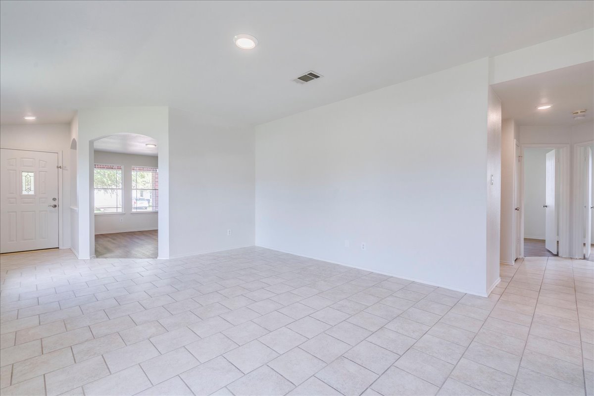 100 Easy Street Hutto, TX 78634 - Photo 10 of 36 Recessed lighting illuminates a versatile living space with clean tile flooring and an inviting archway.