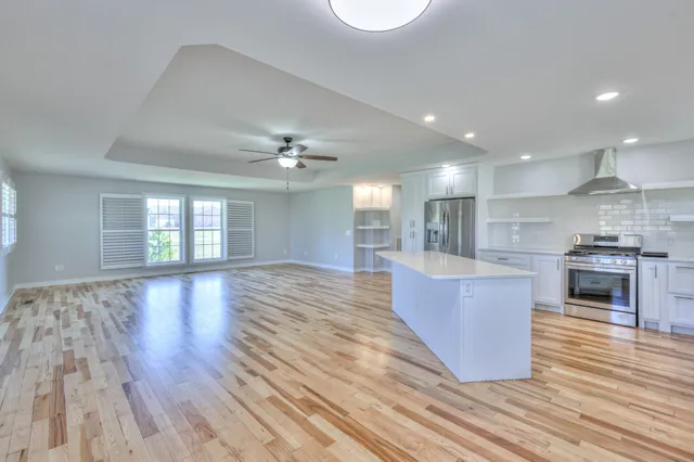 a large kitchen with kitchen island a stove a sink dishwasher and a oven with wooden floor