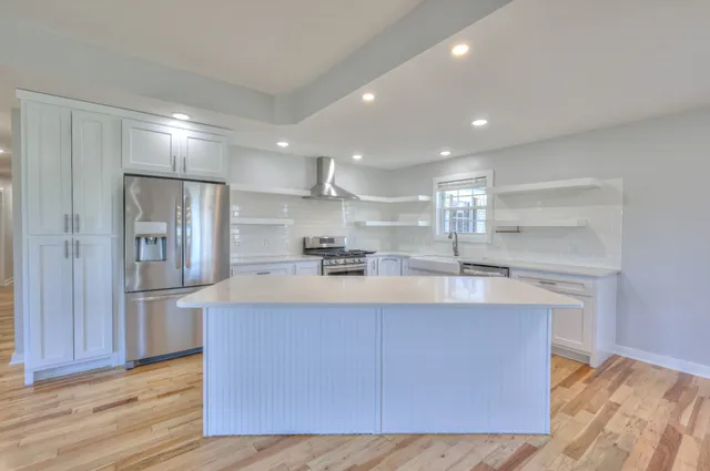 a large kitchen with stainless steel appliances granite countertop a large counter top a sink and a refrigerator