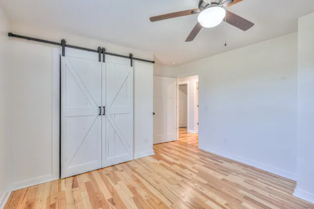 a view of empty room with wooden floor and fan