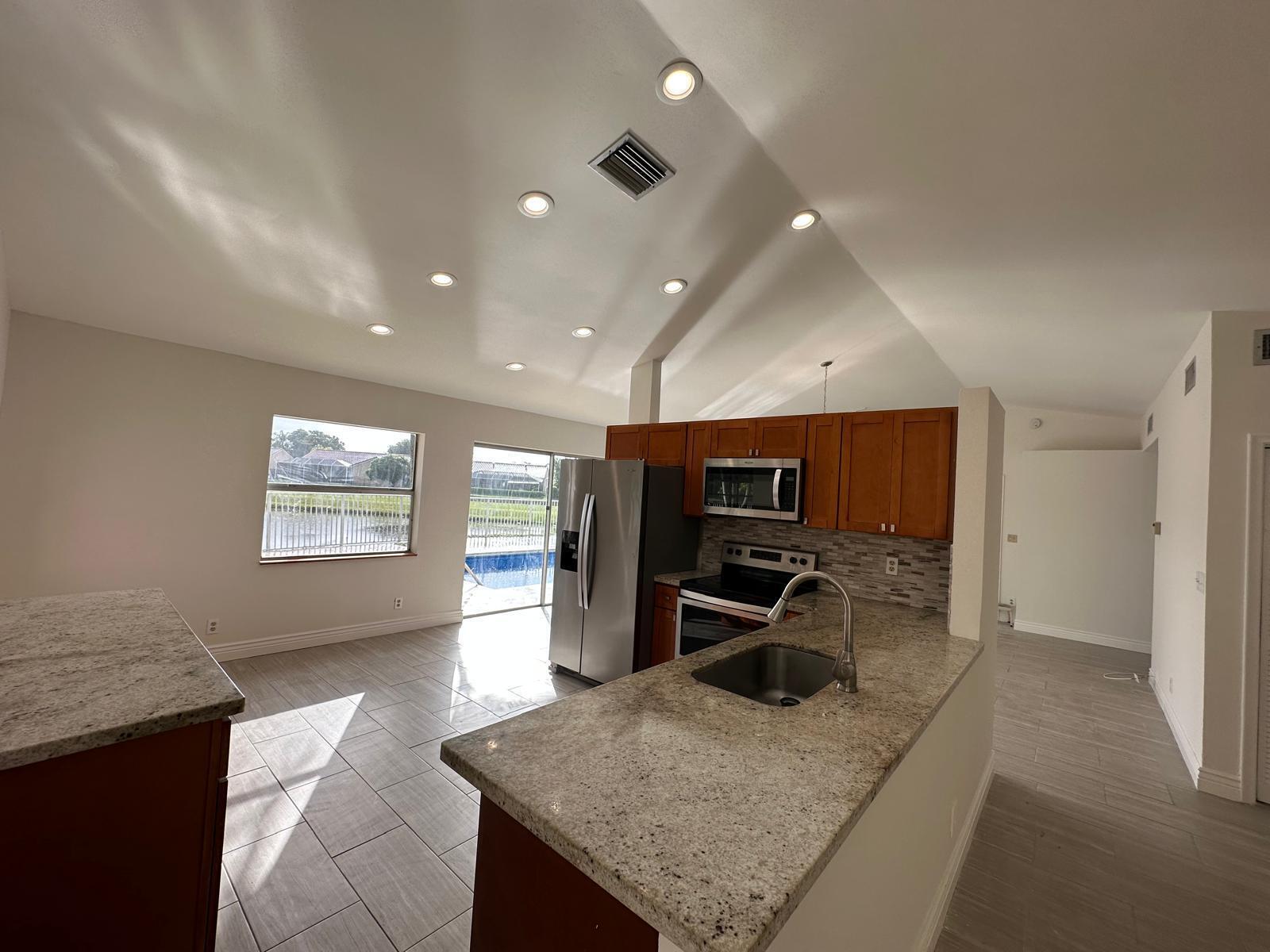 9841 Ridge Creek Road Boca Raton, FL 33496 - Photo 16 of 24 a view of a kitchen with kitchen island a sink wooden floor and a counter top space