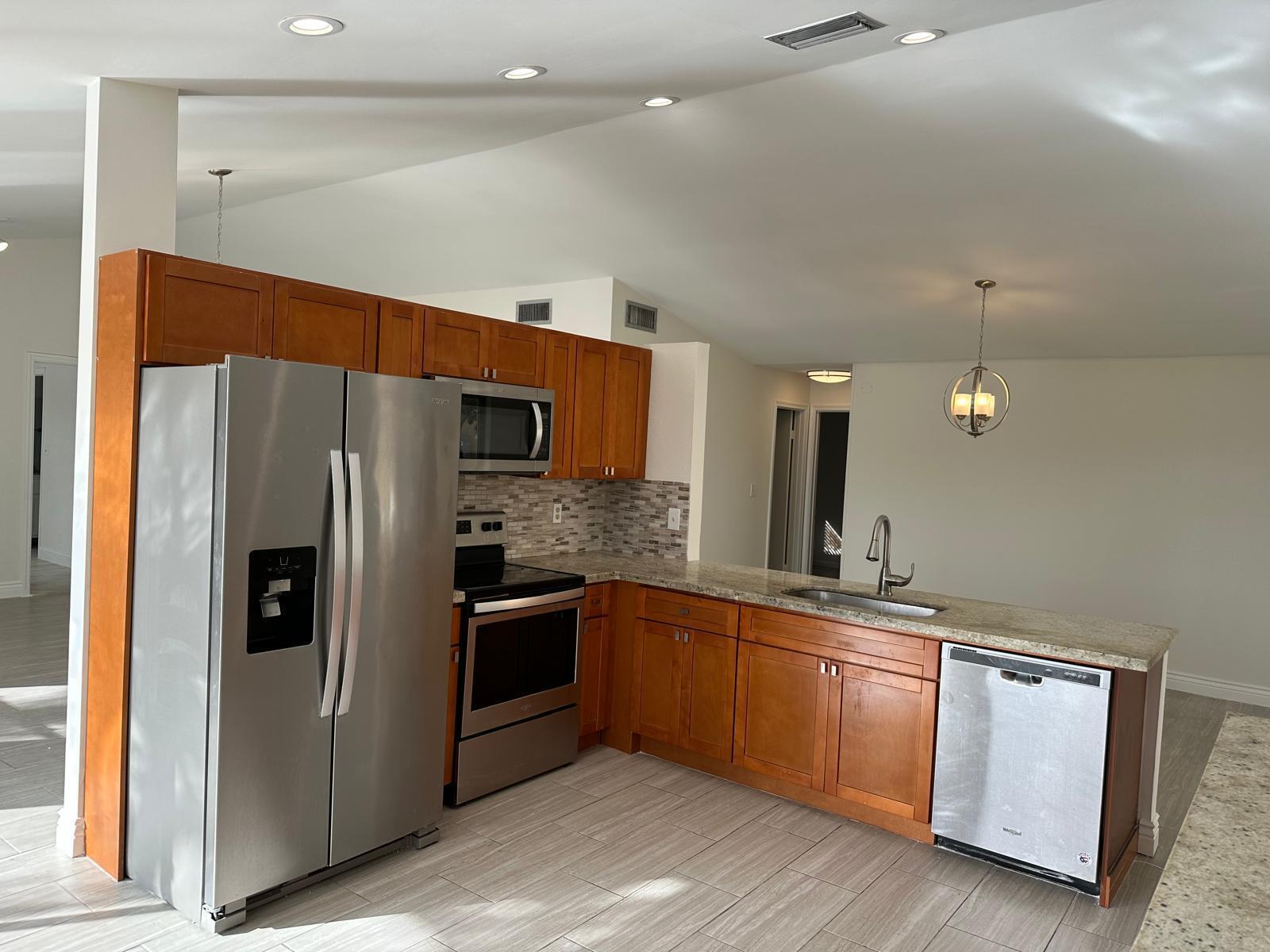 9841 Ridge Creek Road Boca Raton, FL 33496 - Photo 19 of 24 a kitchen with stainless steel appliances kitchen island granite countertop a refrigerator and a sink