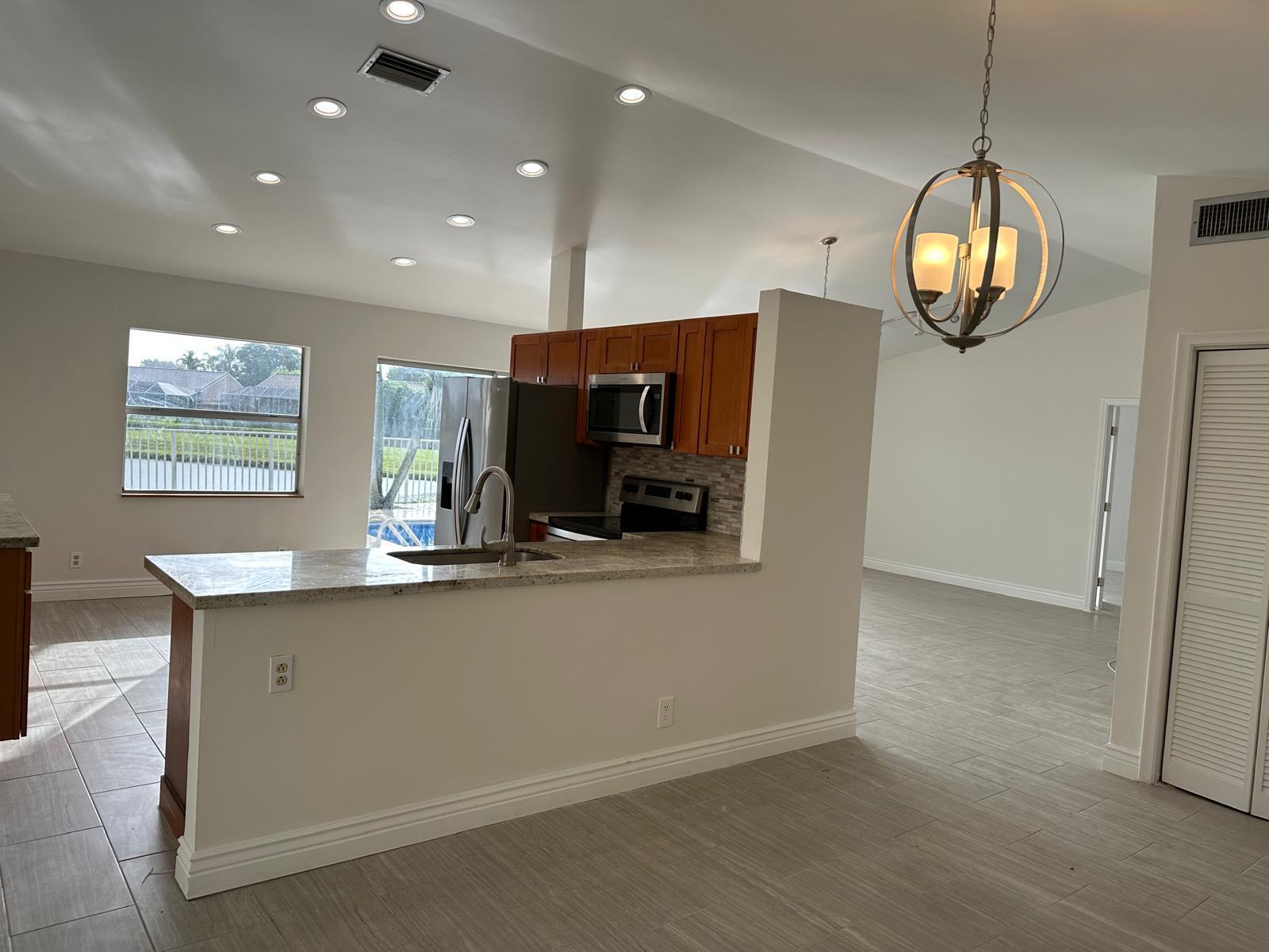 9841 Ridge Creek Road Boca Raton, FL 33496 - Photo 22 of 24 a view of dining room kitchen with furniture and a chandelier