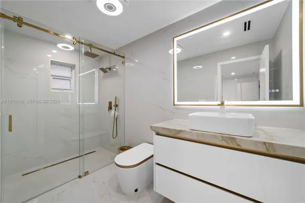 a view of a hallway with stainless steel appliances refrigerator and cabinets