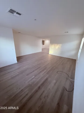 a view of a big room with wooden floor and windows