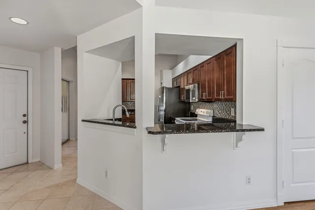 a kitchen with stainless steel appliances granite countertop a refrigerator and a stove top oven