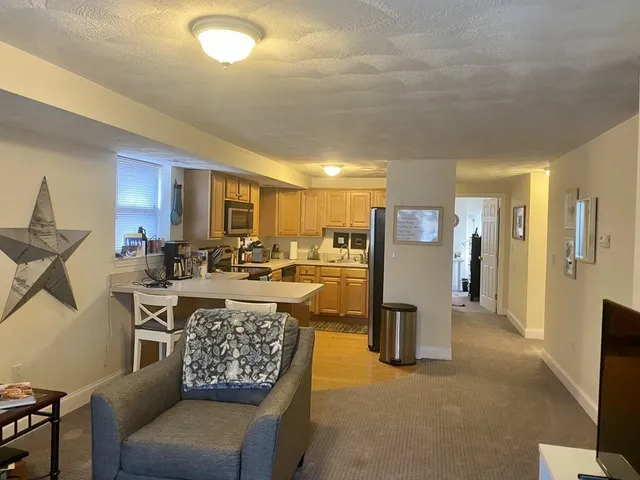 a living room with furniture a refrigerator and kitchen view