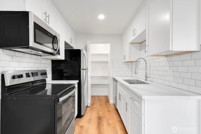 a kitchen with stainless steel appliances a sink dishwasher stove and oven with wooden floor