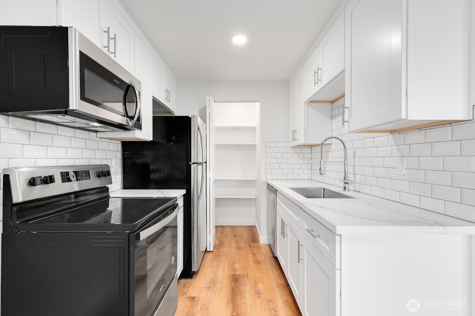 2020 Grant Avenue South, Unit D204 Renton, WA 98055 - Photo 4 of 16 a kitchen with stainless steel appliances a sink dishwasher stove and oven with wooden floor