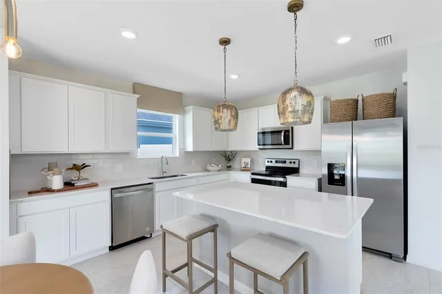 a kitchen with stainless steel appliances a sink a stove a refrigerator a center island and cabinets