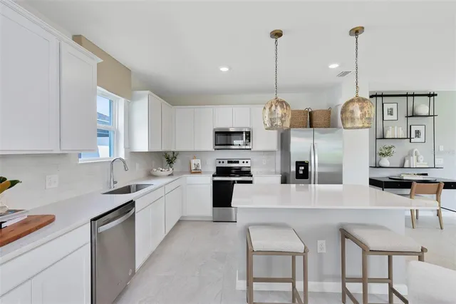 a kitchen with stainless steel appliances granite countertop a sink a stove a refrigerator and island with wooden floor