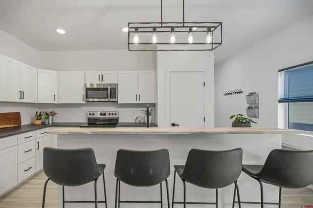 a kitchen with stainless steel appliances a stove a sink and dishwasher a refrigerator with wooden floor