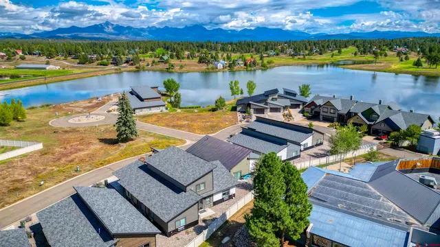 a view of a patio with couches table and chairs under an umbrella with large trees