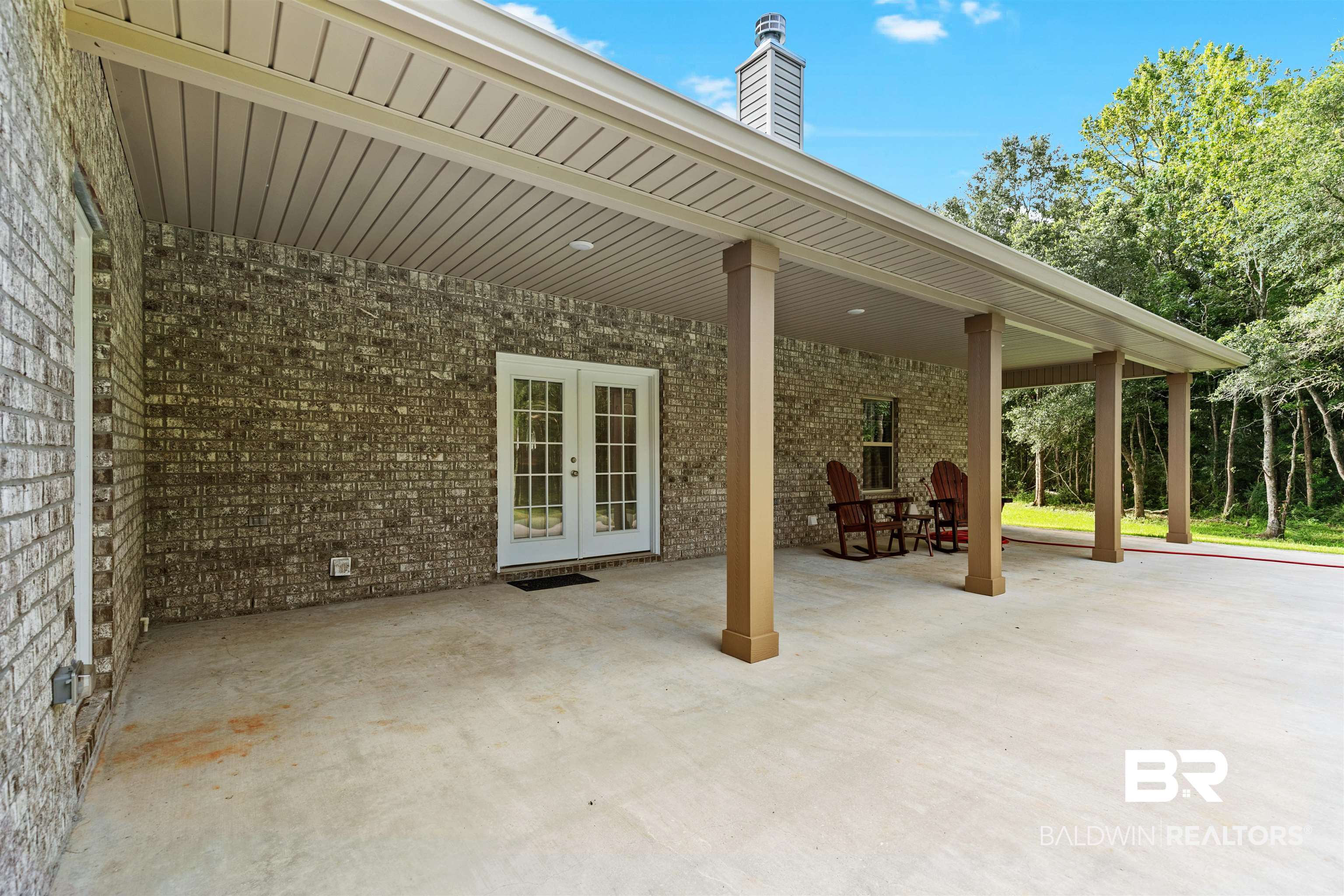 8552 March Road Irvington, AL 36544 - Photo 25 of 28 Expansive covered patio featuring a concrete surface, a brick exterior wall, and white double French doors