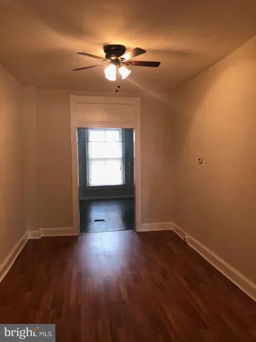 an empty room with wooden floor chandelier fan and windows