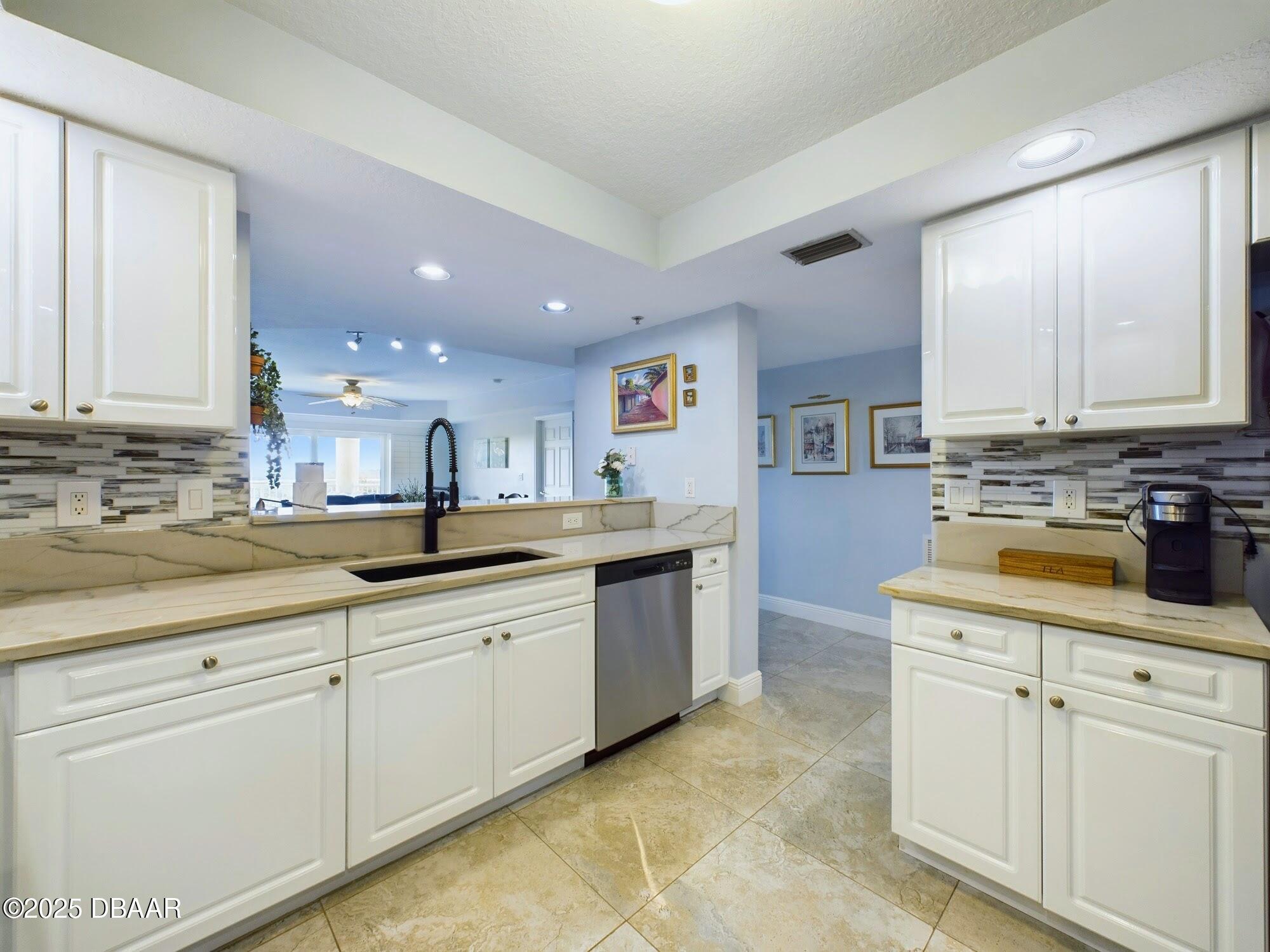 4670 Links Village Drive, Unit C601 Ponce Inlet, FL 32127 - Photo 9 of 68 a kitchen with granite countertop white cabinets and white appliances