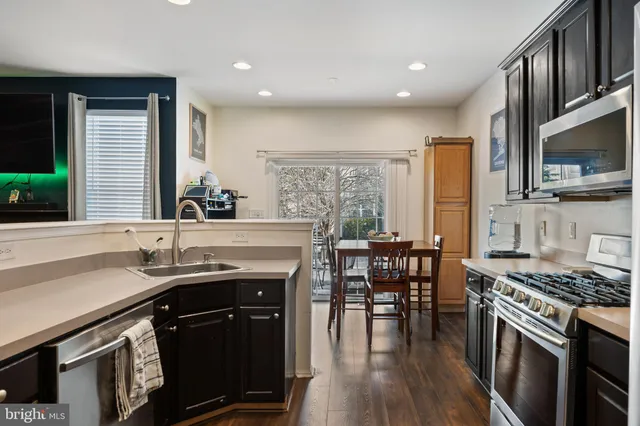 a kitchen with stainless steel appliances granite countertop a stove a sink a microwave a dining table and chairs