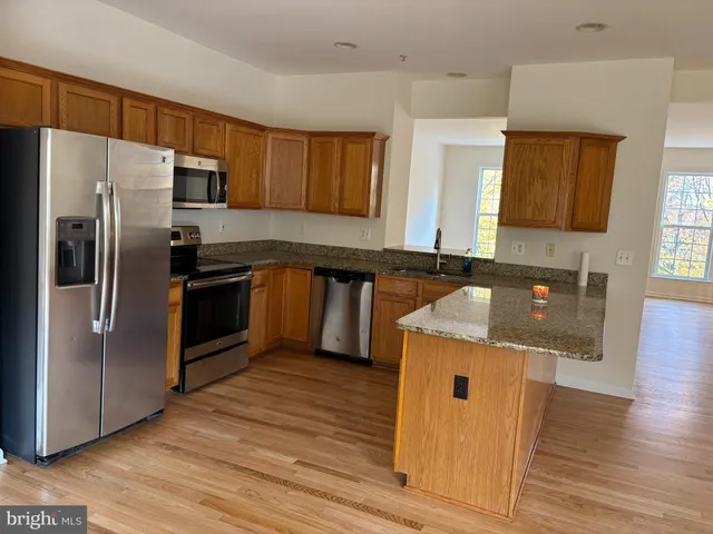 a kitchen with stainless steel appliances granite countertop a refrigerator and a stove top oven