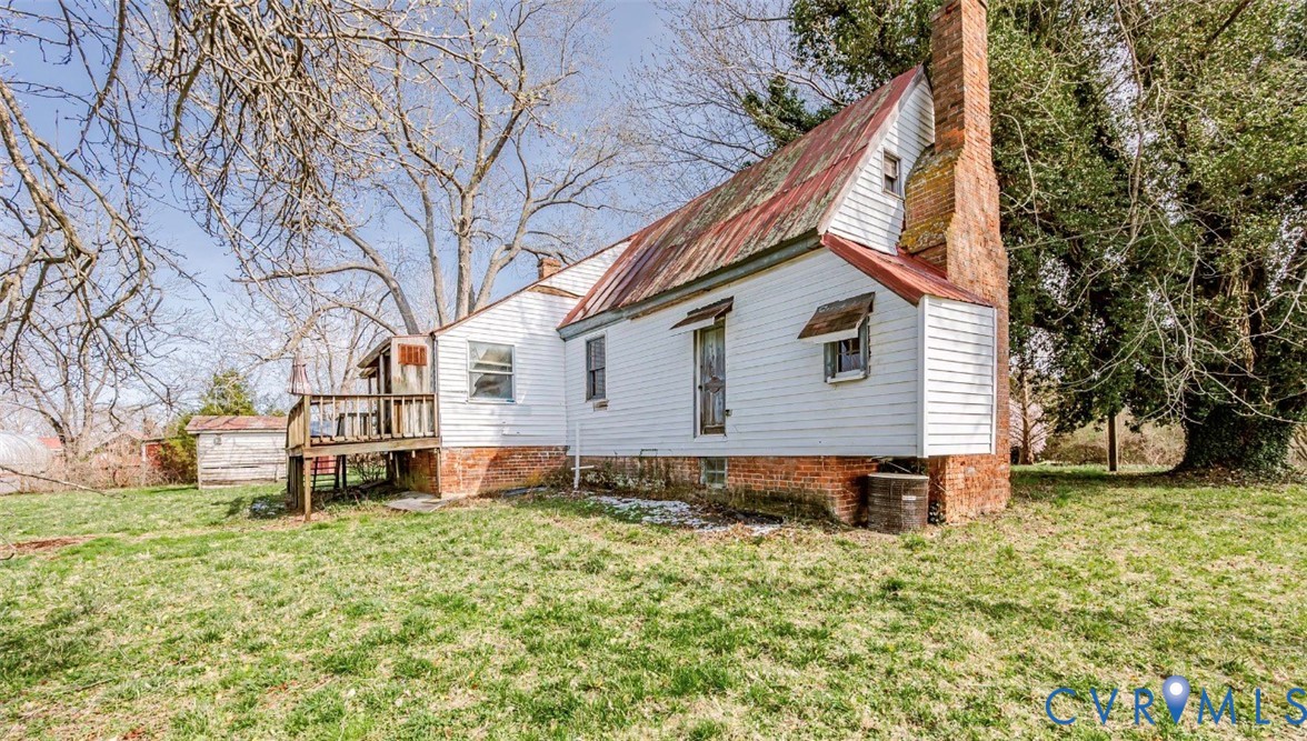 Rear view of house featuring a yard, a chimney, an