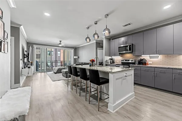 a kitchen with stainless steel appliances kitchen island granite countertop a stove top oven a sink a dining table and chairs with wooden floor