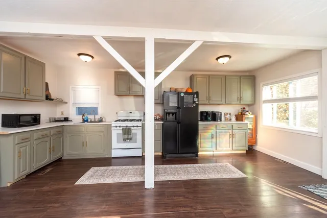 a kitchen with stainless steel appliances granite countertop a refrigerator a sink dishwasher a stove and white cabinets with wooden floor