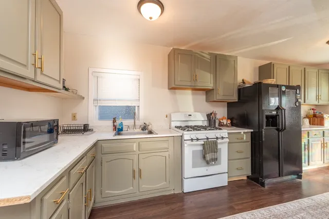 a kitchen with stainless steel appliances a stove a sink dishwasher a refrigerator and cabinets with wooden floor